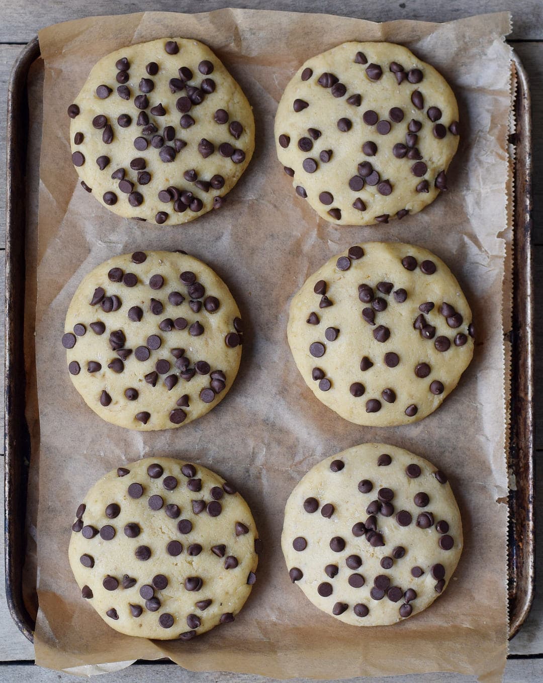 6 ungebackene vegane Kekse mit Schokodrops auf Backblech