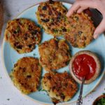 hand greift nach einem von 6 veganen kartoffelpuffern auf einem türkisen teller