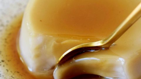 Flan mit Karamell und Löffel auf einem kleinen Teller