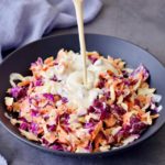 Veganes Dressing wird über Coleslaw (amerikanischer Krautsalat) gegossen