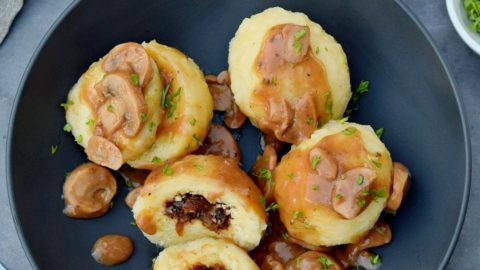 4 Kartoffelklöße in schwarzer Schüssel mit Pilzsoße