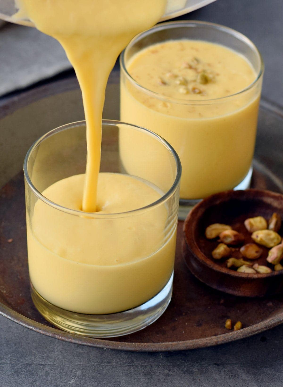 mango lassi is being poured in a glass