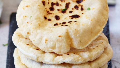 Hand greift nach einem Pita Brot Stapel