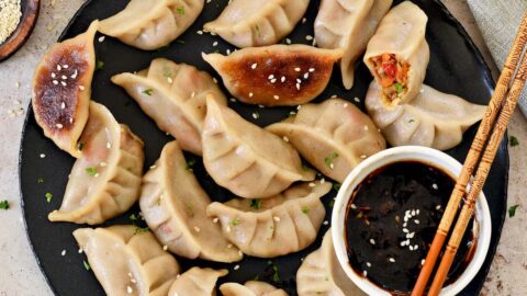 Gyoza Teigtaschen auf einem schwarzen Teller mit Szechuan Sauce