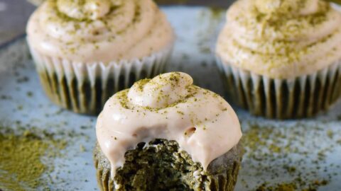 Vegane Matcha Cupcakes mit Frosting auf einem Teller und ein Stück angebissen