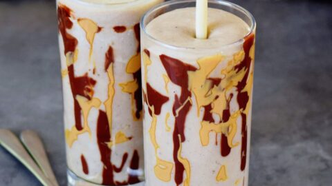 Bananen Milchshake in 2 Gläsern beträufelt mit Erdnussmus und Schokolade