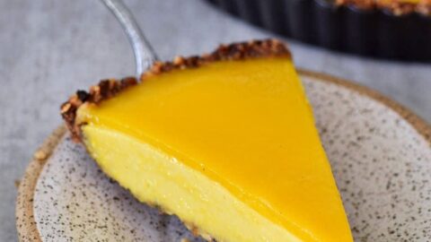 Ein Stück veganer Mango Käsekuchen auf kleinem Teller