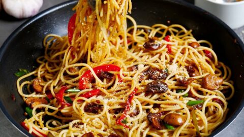 Spaghetti Aglio e Olio mit Pilzen und Paprika in schwarzer Pfanne