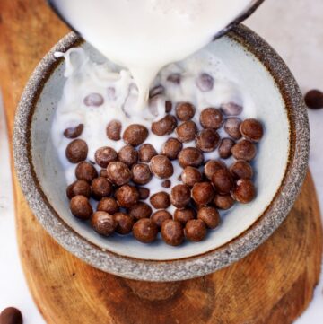 Pflanzenmilch wird in Schale mit selbstgemachten Choco Pops gegossen