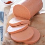 vegane Lyoner Wurst aufgeschnitten auf Holzbrett