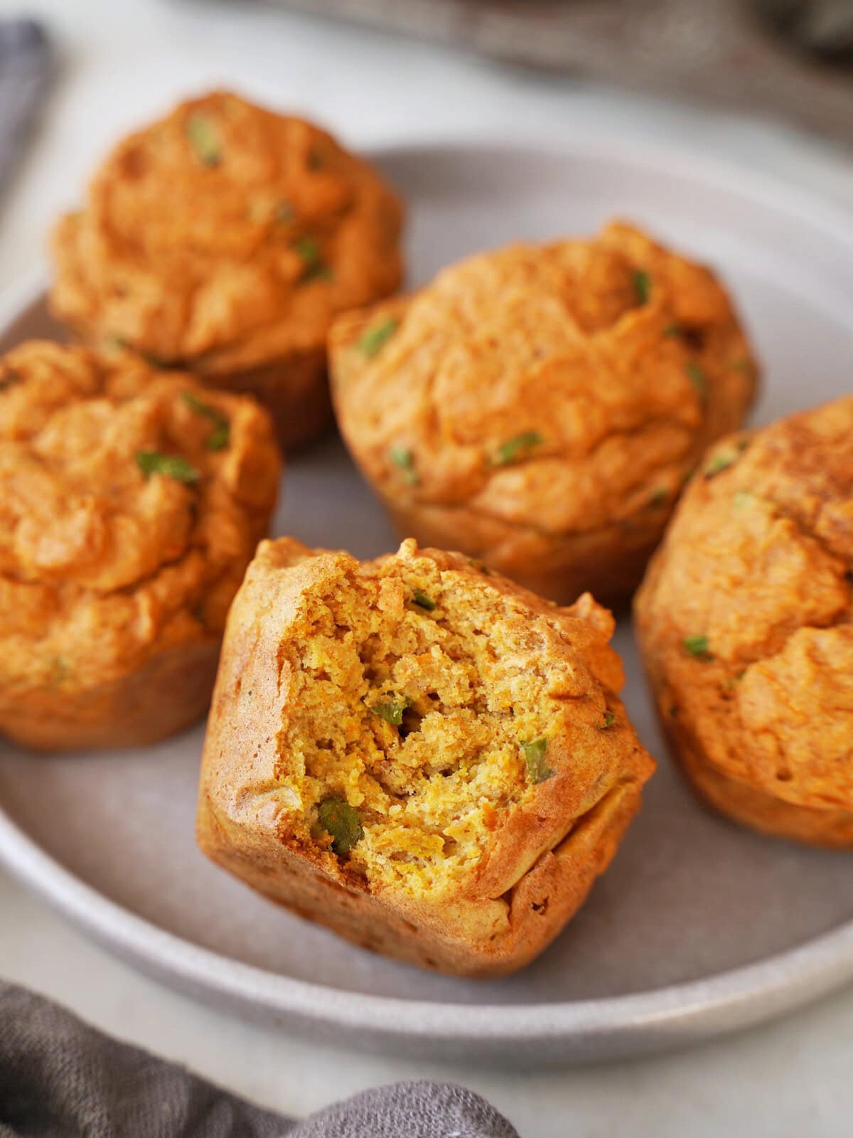 Ein Teller mit 5 goldbraunen Linsen Muffins, einer davon ist angebissen