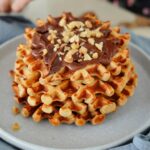 Turm aus roten Linsen Waffeln mit Schokocreme und gehackten Nüssen