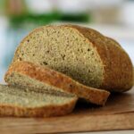 Erbsenbrot auf Holzbrett mit zwei Scheiben vorne dran