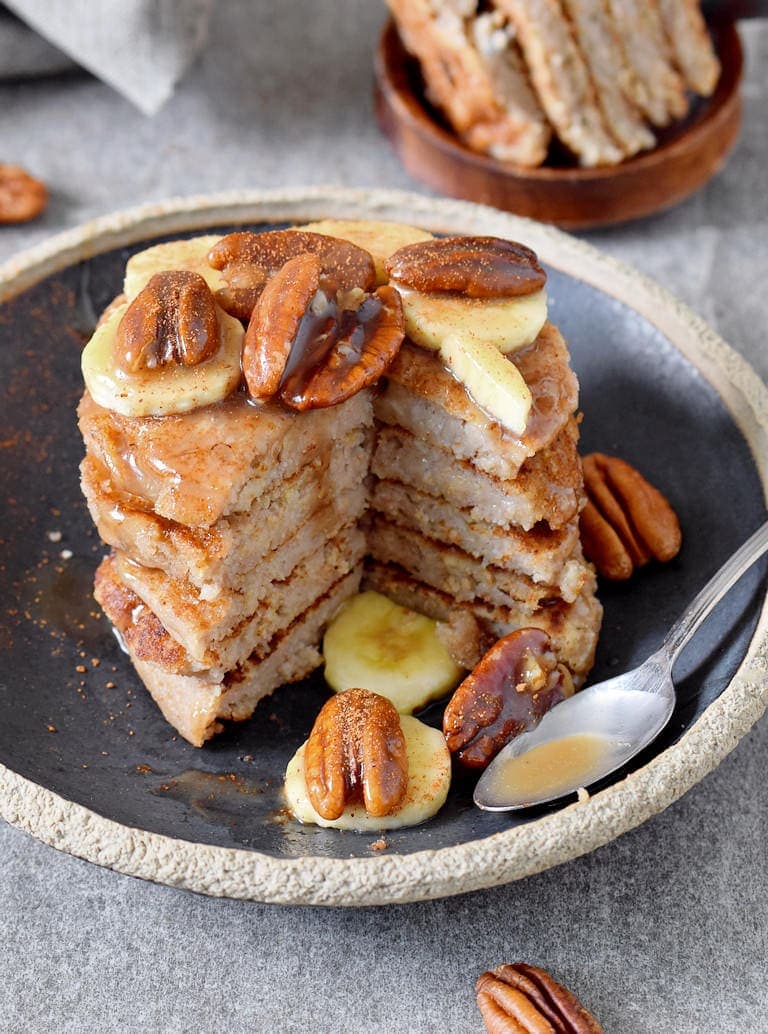 stack of homemade oat flour pancakes with pecans and maple syrup