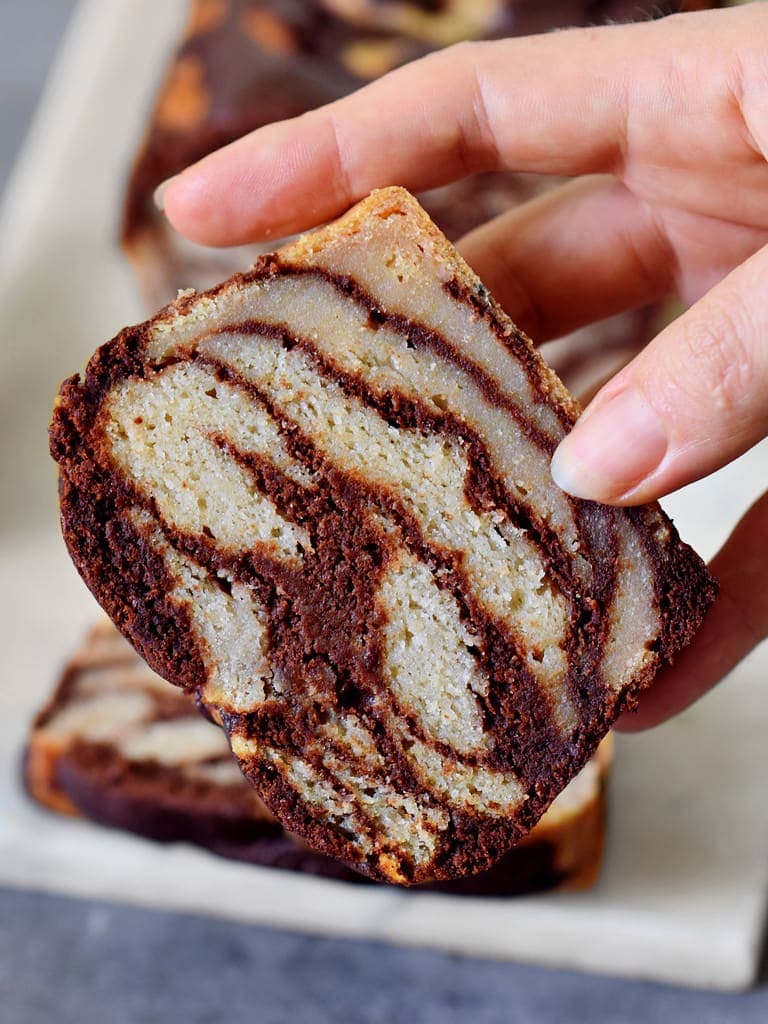 hand holding a piece of banana cake with chocolate marble