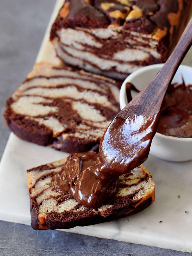 spoon with vegan chocolate spread on a slice of marble banana bread