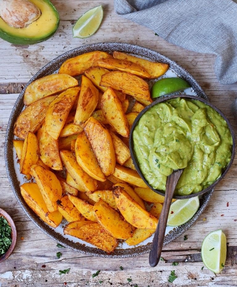Crispy oven-baked potato wedges in a bowl with guacamole