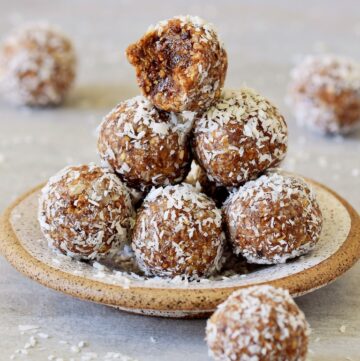 healthy vegan bliss balls on small plate rolled in coconut