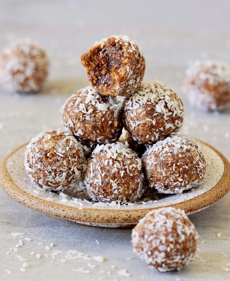 healthy vegan bliss balls on small plate rolled in coconut