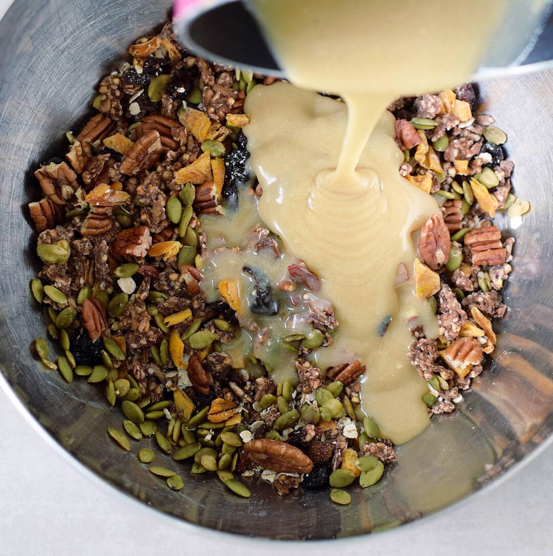 Pouring wet ingredients into bowl with nuts and seeds