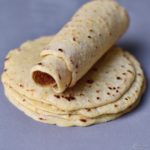 Homemade stack of gluten free tortillas with the top one rolled up