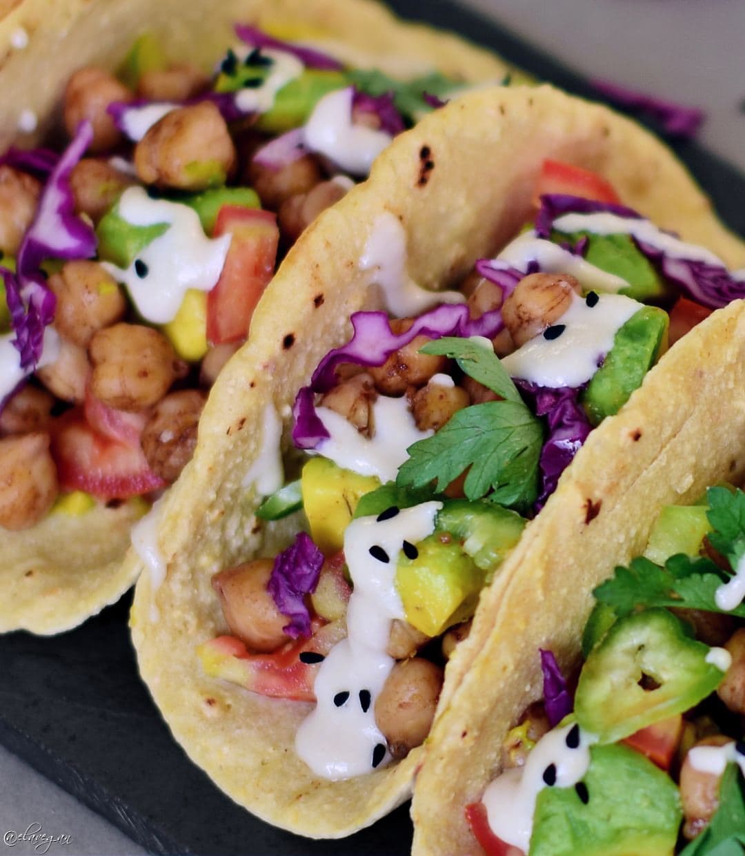 Close-up of vegan tacos with avocado, veggies, and a tahini dressing