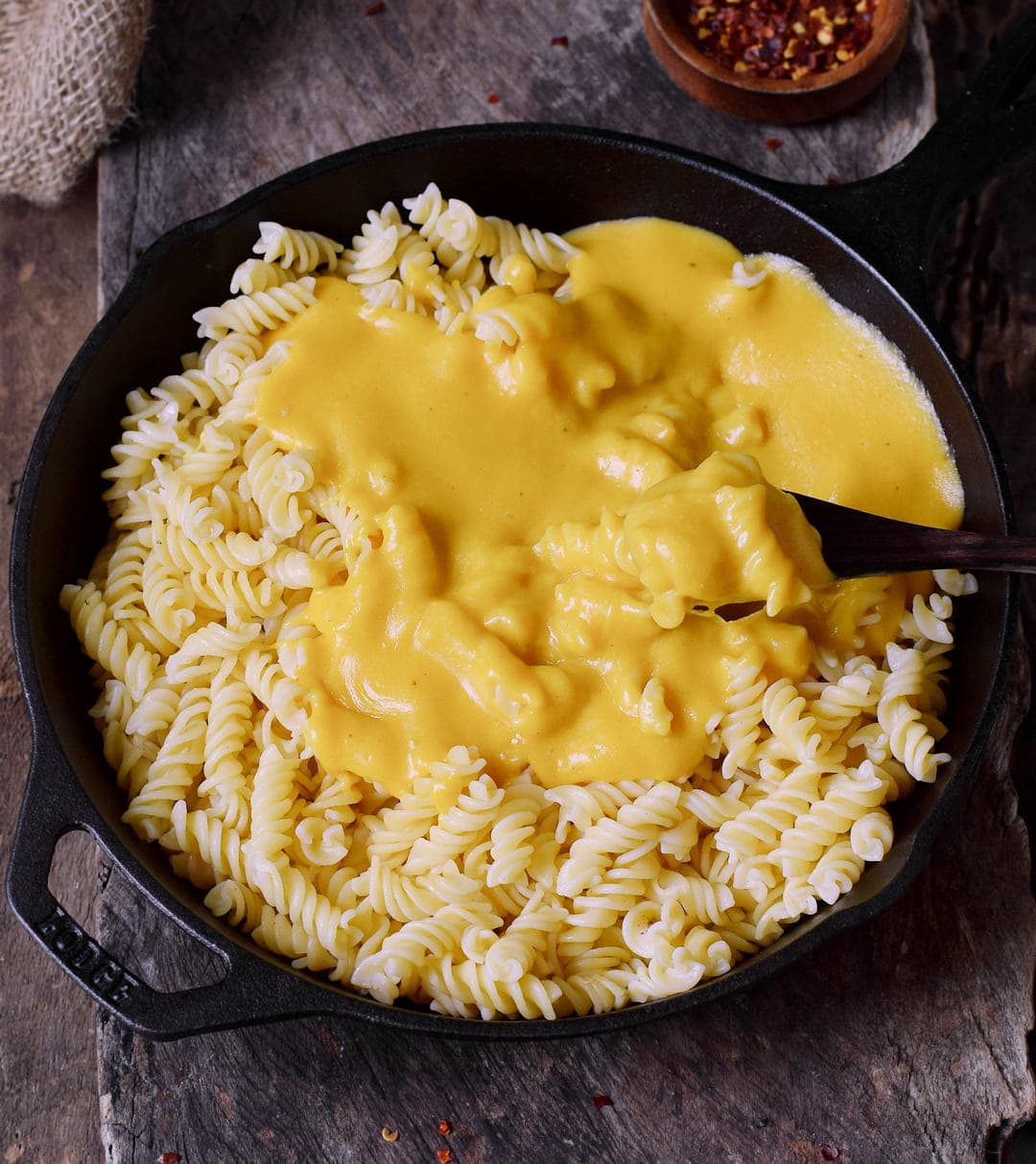 Mac'n cheese sauce with pasta and spoon in black skillet