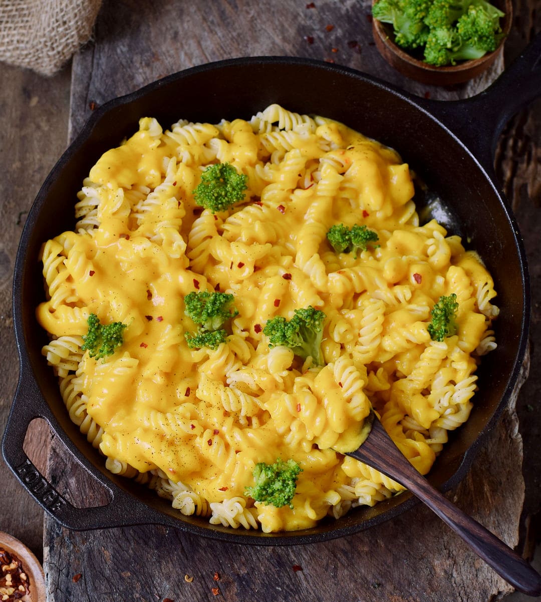 Plant-based cheese sauce with pasta and broccoli in a black skillet