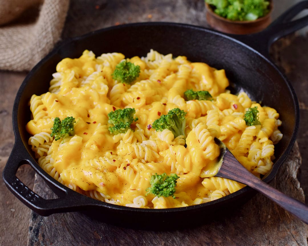 Gluten-free pasta with cheeze sauce and broccoli in black skillet