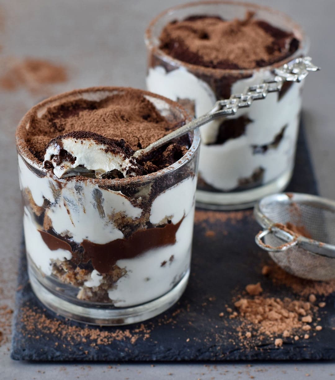 Italian dessert in a jar layered in 2 glass jars with cocoa dust and spoon