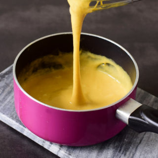 Easy vegan cheese sauce in a pink pan with a whisk.