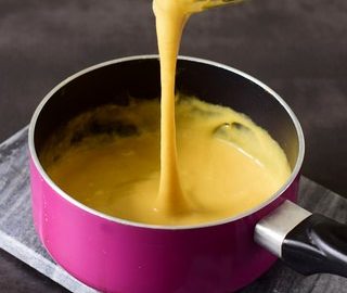 vegan cheese sauce in pink saucepan with cheese pull