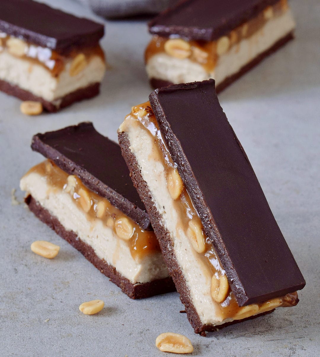 Close-up candy bars with a brownie base, cashew cream, peanut caramel and dairy-free chocolate