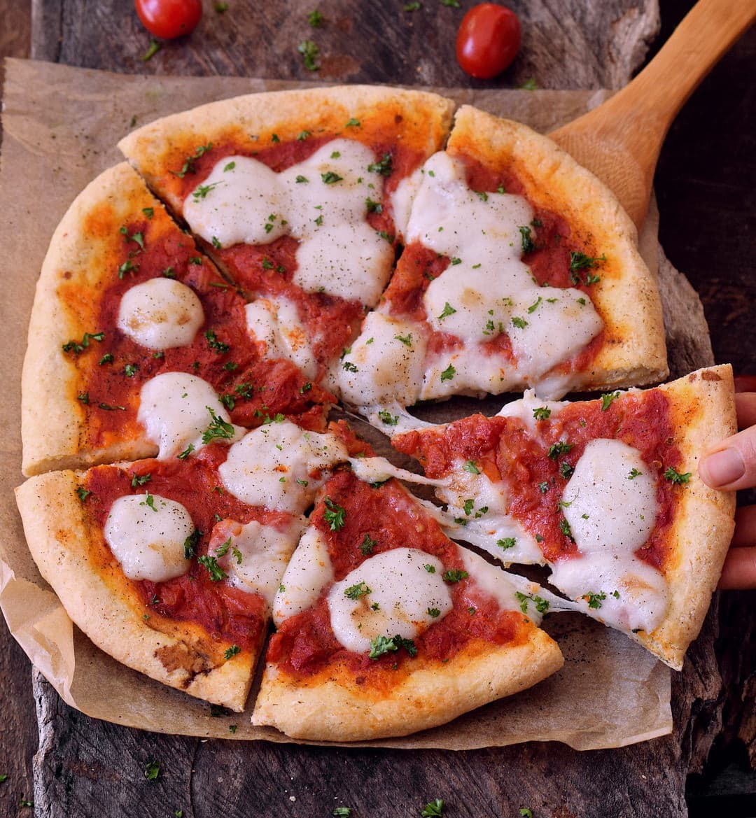 Best gluten-free pizza crust cut into 6 pieces with tomato sauce and vegan mozzarella. Gum-free, dairy-free, egg-free pizza dough