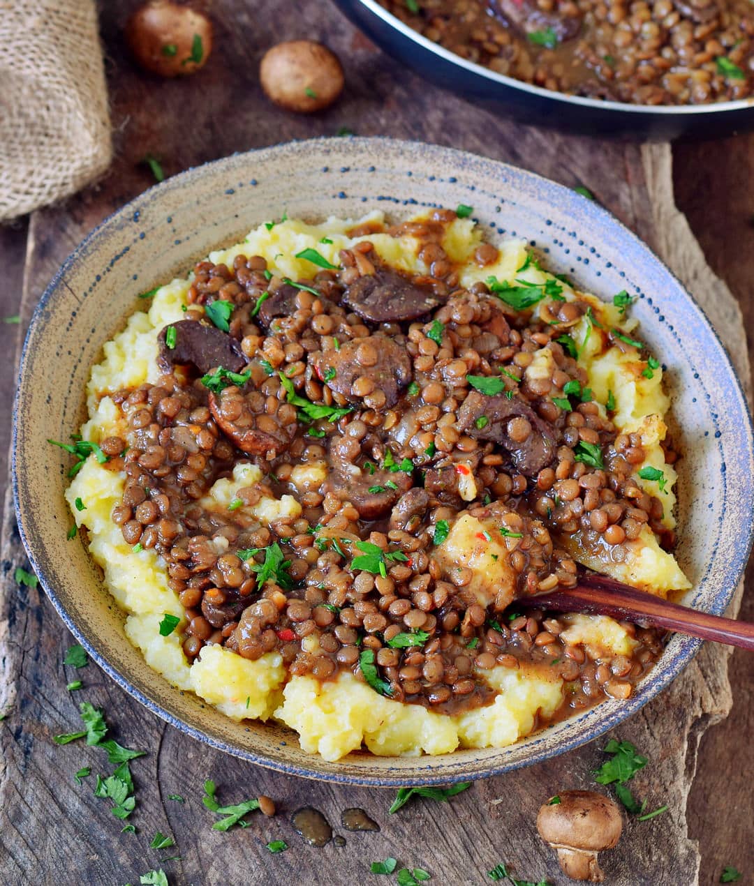 Mashed potatoes in a bowl with lentils and mushrooms.