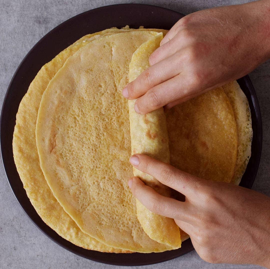 hands rolling up a tortilla with enchilada filling