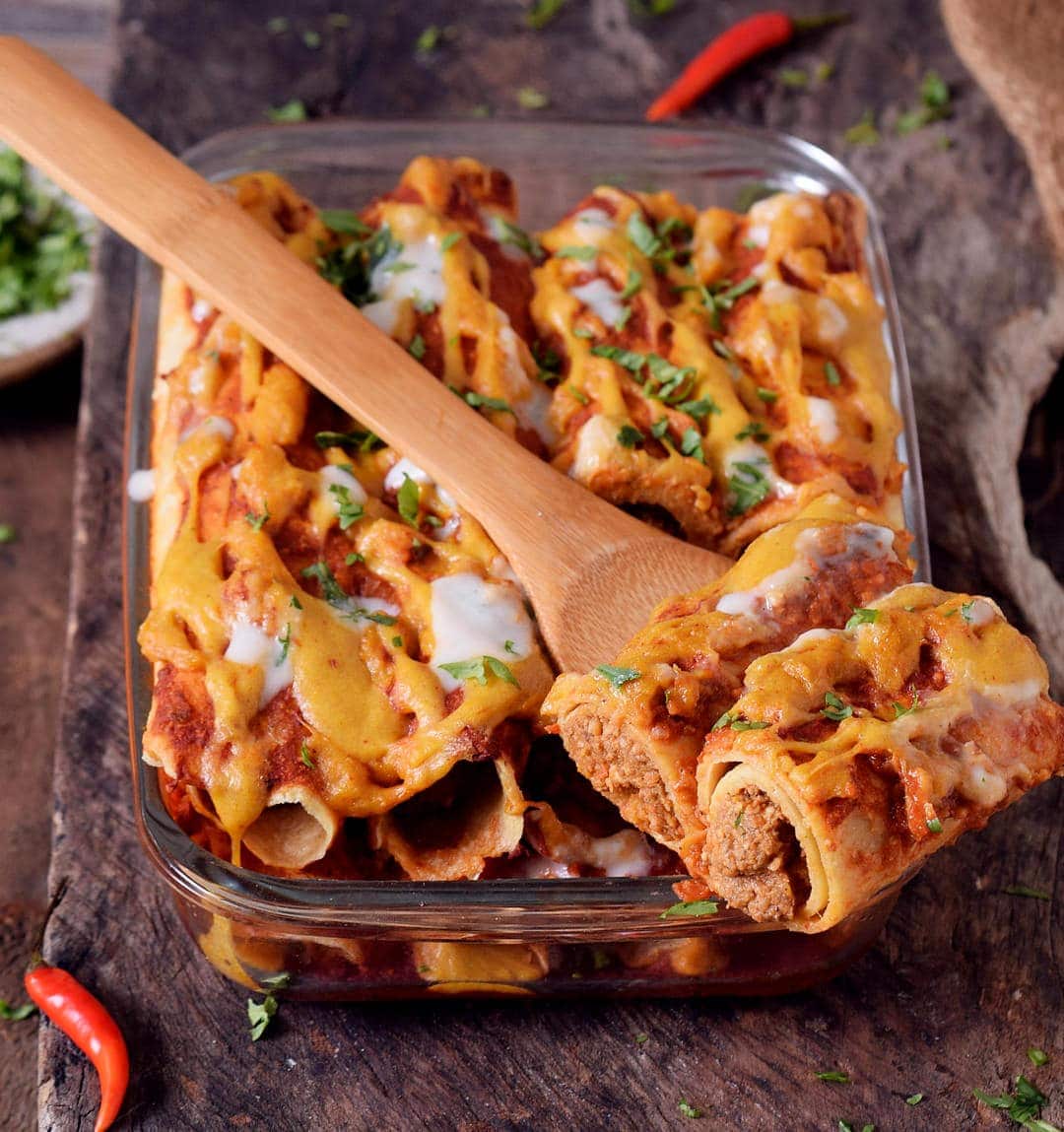 vegan lentil enchiladas in baking dish and wooden spoon