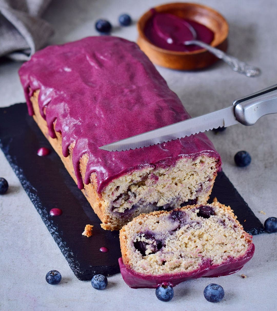cutting a loaf of blueberry bread with a knife