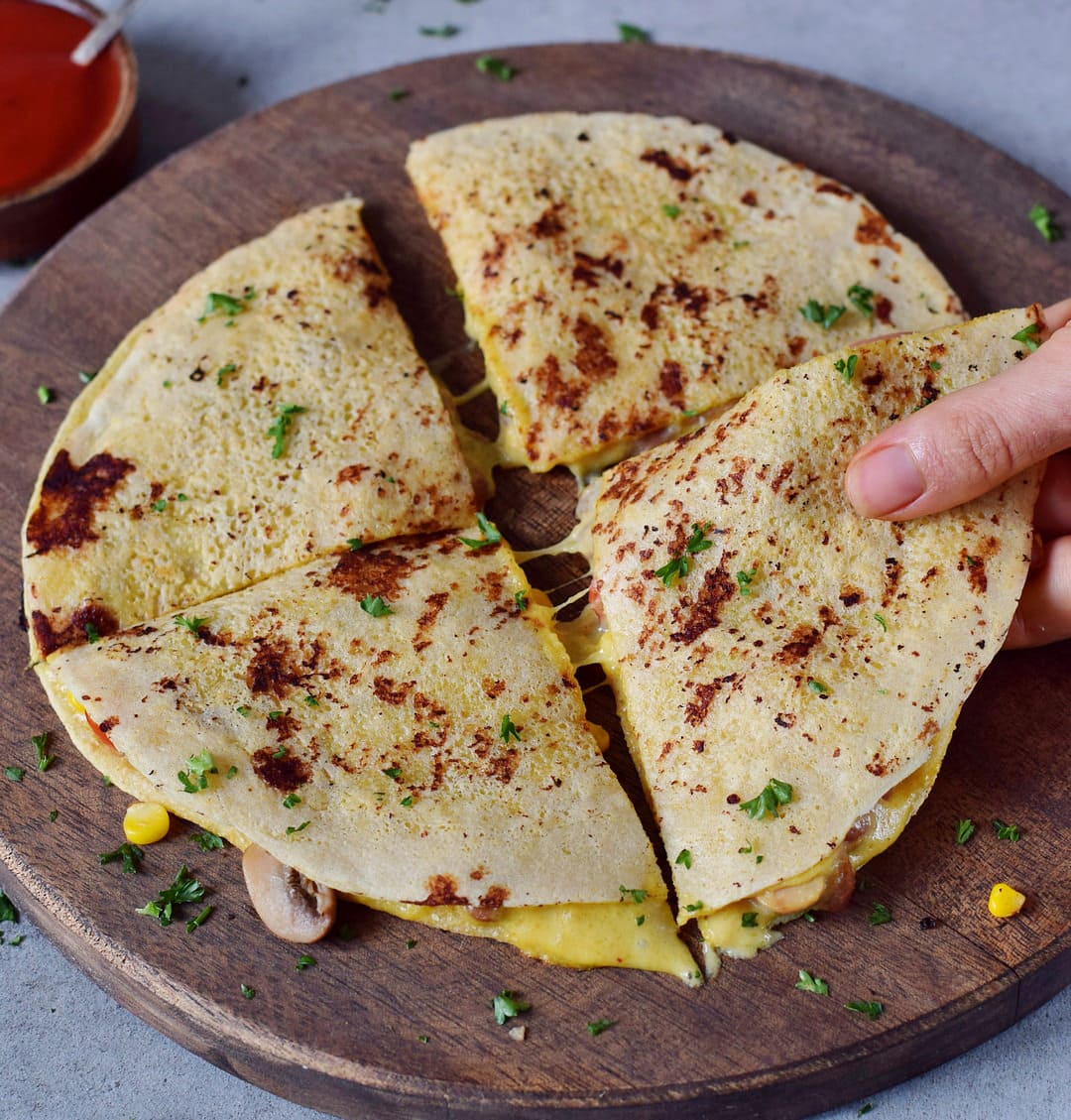 vegan quesadillas on a cutting board filled with plant-based cheese