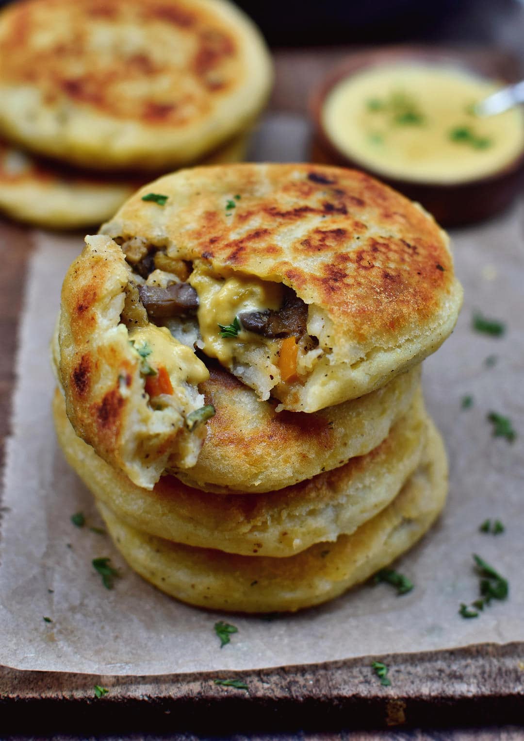 Stuffed potato cakes (arepas) with mushrooms, peppers, and vegan cheese sauce