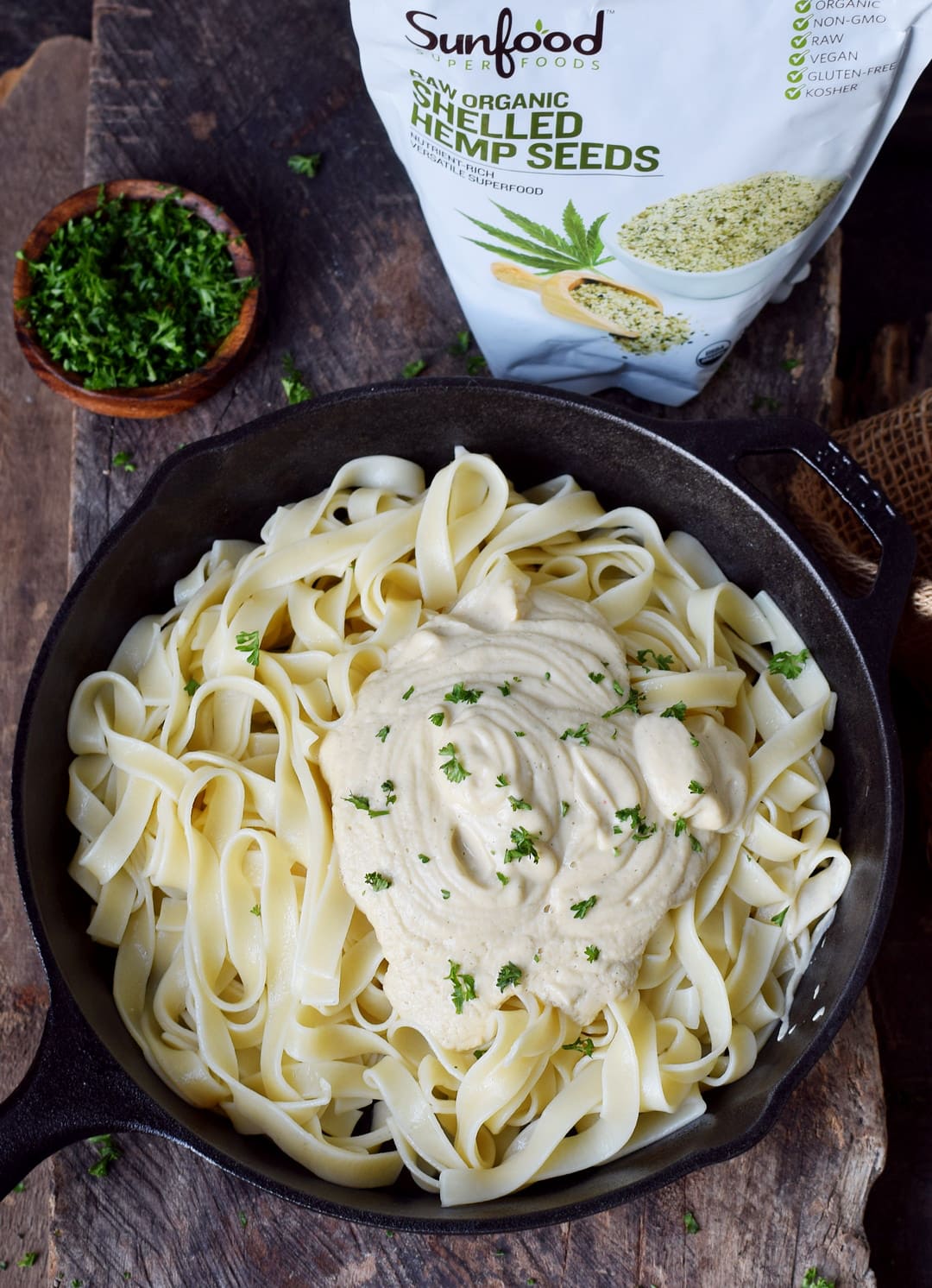 White creamy sauce on Fettuccine pasta with a bag of Sunfoods hemp seeds 