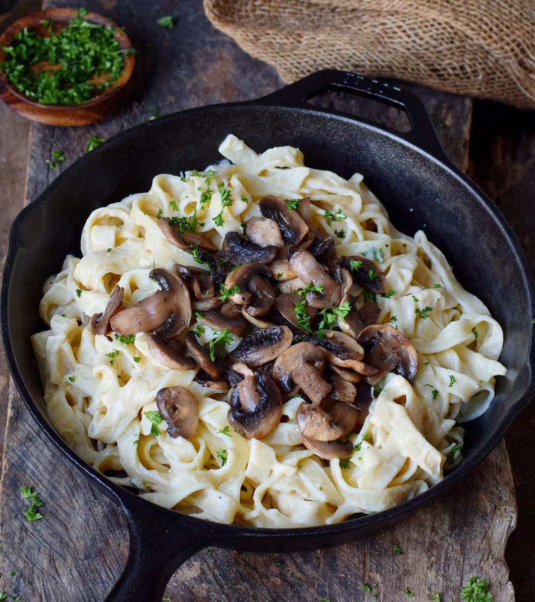 Fettuccine and mushrooms with white sauce in a black skillet