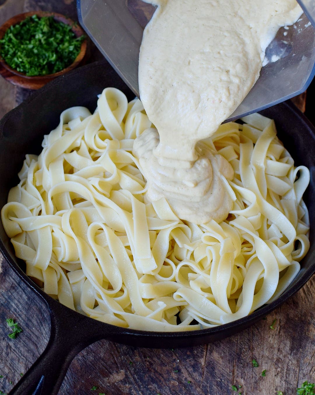 Pouring cauliflower sauce over Fettuccine pasta