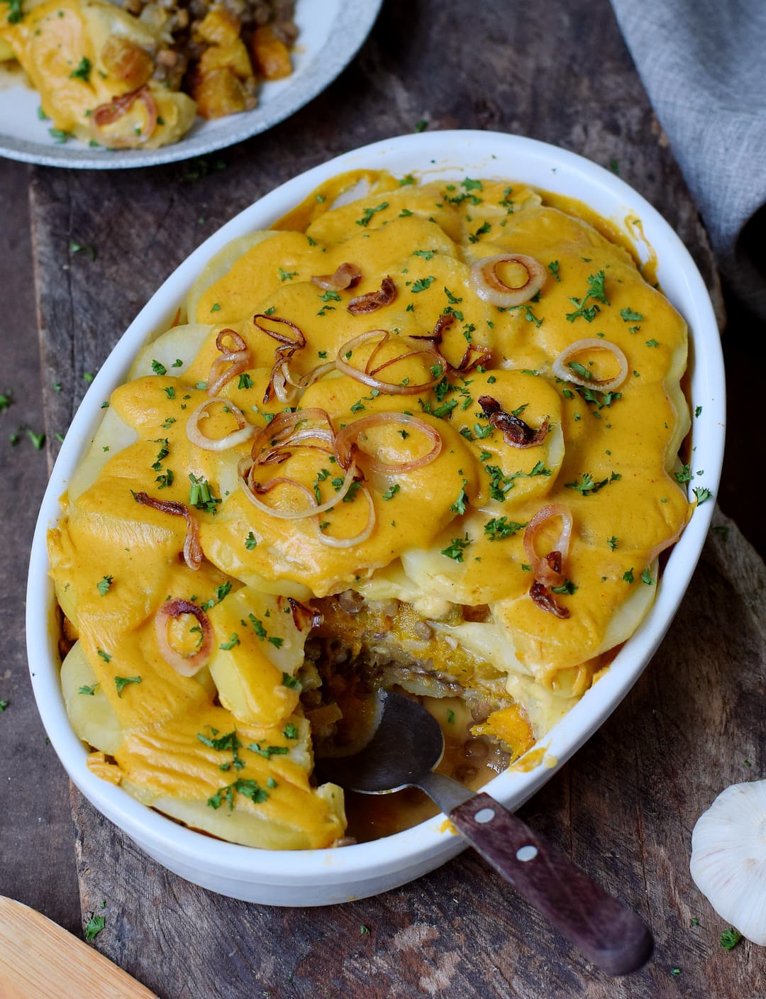 gluten-free potato casserole with pumpkin and lentils in a round baking dish with fried onion rings