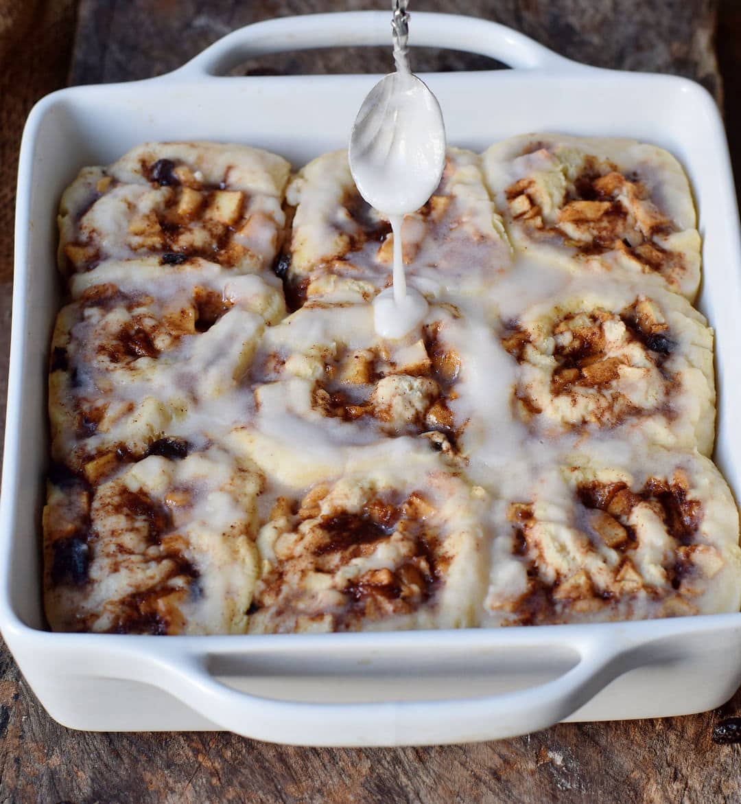 apple cinnamon rolls in a baking dish with icing sugar after baking