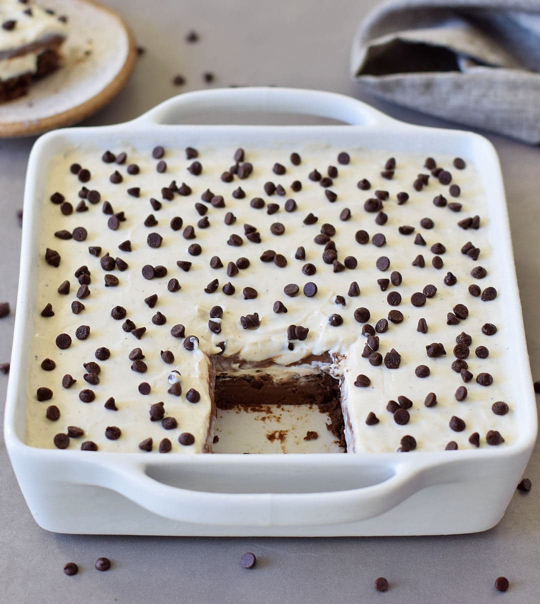 chocolate lasagna with vegan mini chocolate chips in a white baking dish with a piece cut out