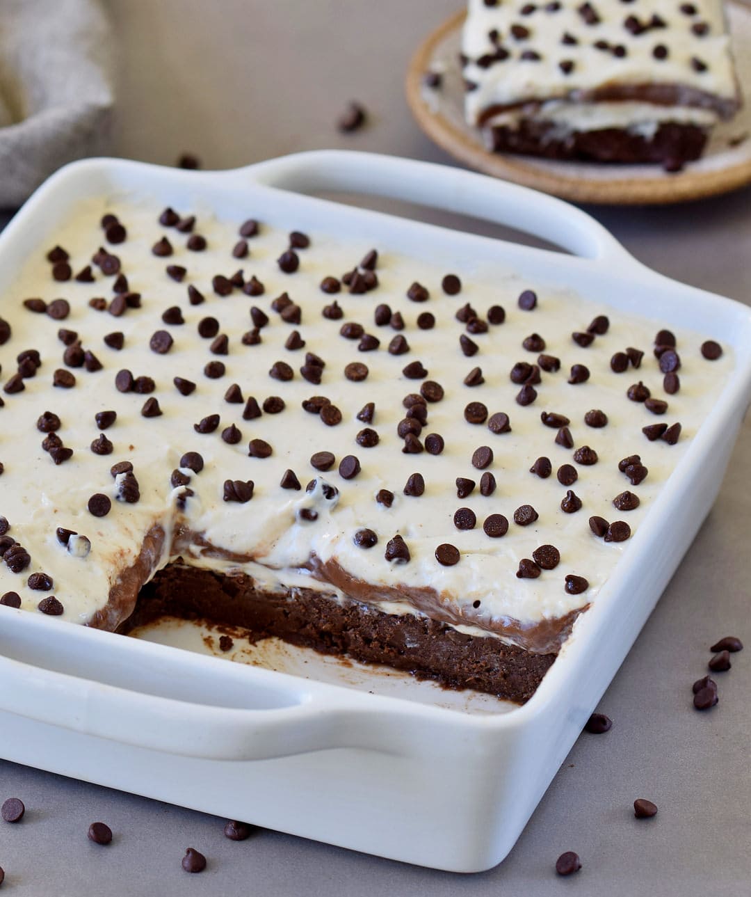 chocolate lasagna with vegan mini chocolate chips in a white baking dish with two pieces cut out