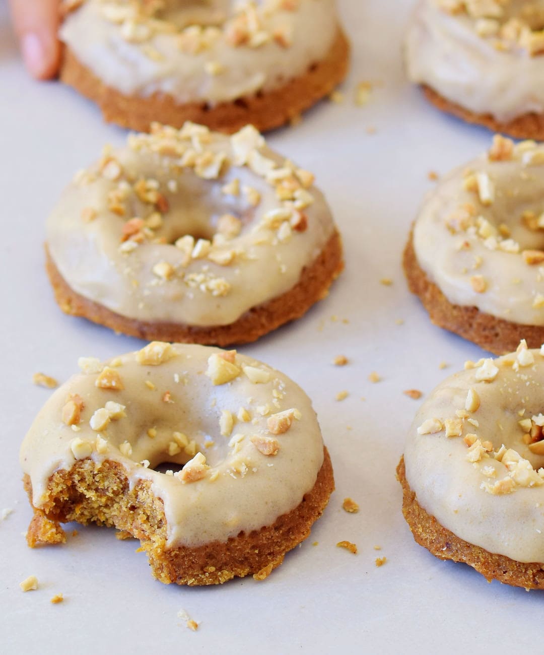 hand grabbing vegan carrot cake donuts with gingerbread flavor and frosting