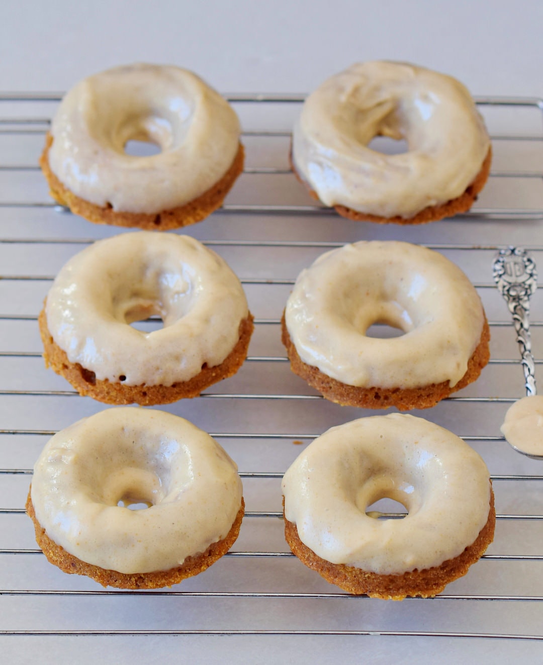 healthy vegan carrot cake donuts with gingerbread flavor and frosting on a wire rack