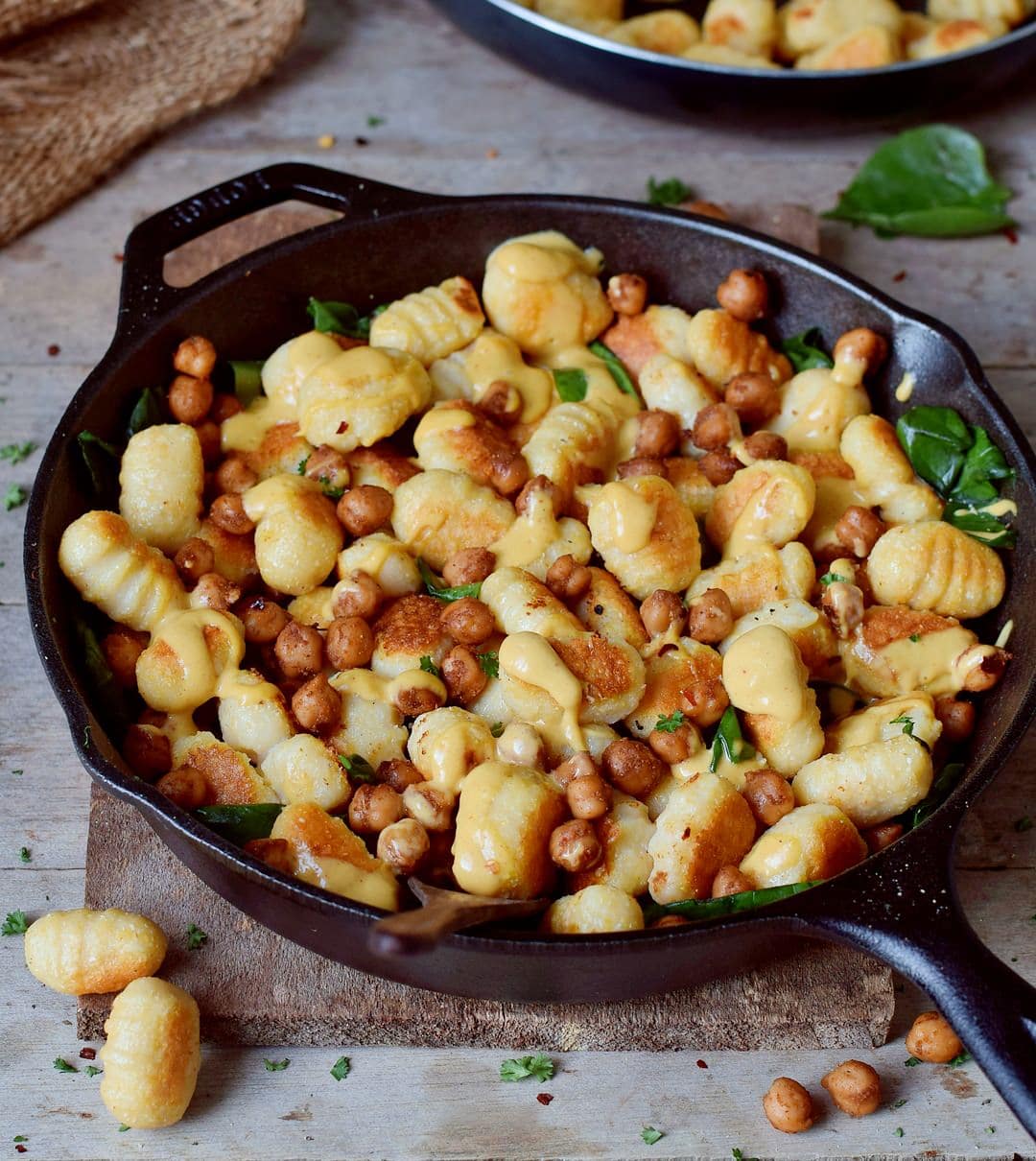 Close-up of homemade gluten-free vegan gnocchi with roasted chickpeas spinach and cheese sauce in a pan